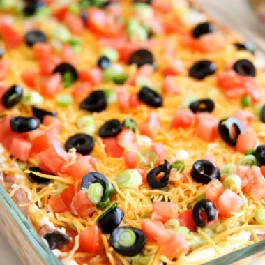 Ultimate seven layer bean dip with colorful layers and garnishes.