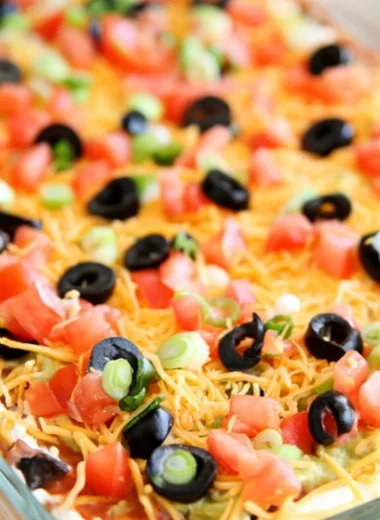 Ultimate seven layer bean dip with colorful layers and garnishes.