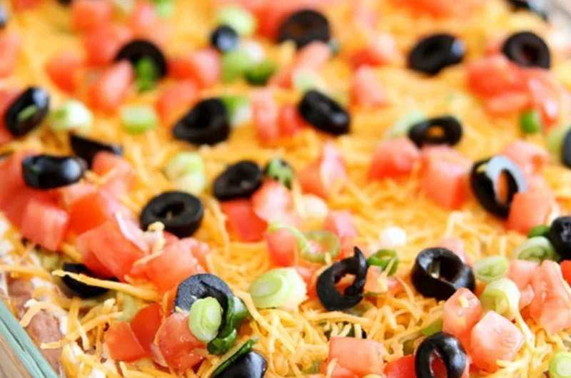 Ultimate seven layer bean dip with colorful layers and garnishes.